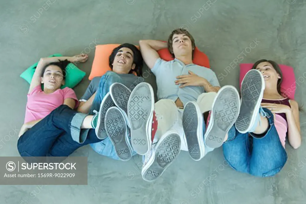 Teenage friends lying on floor with feet in the air, view from directly above