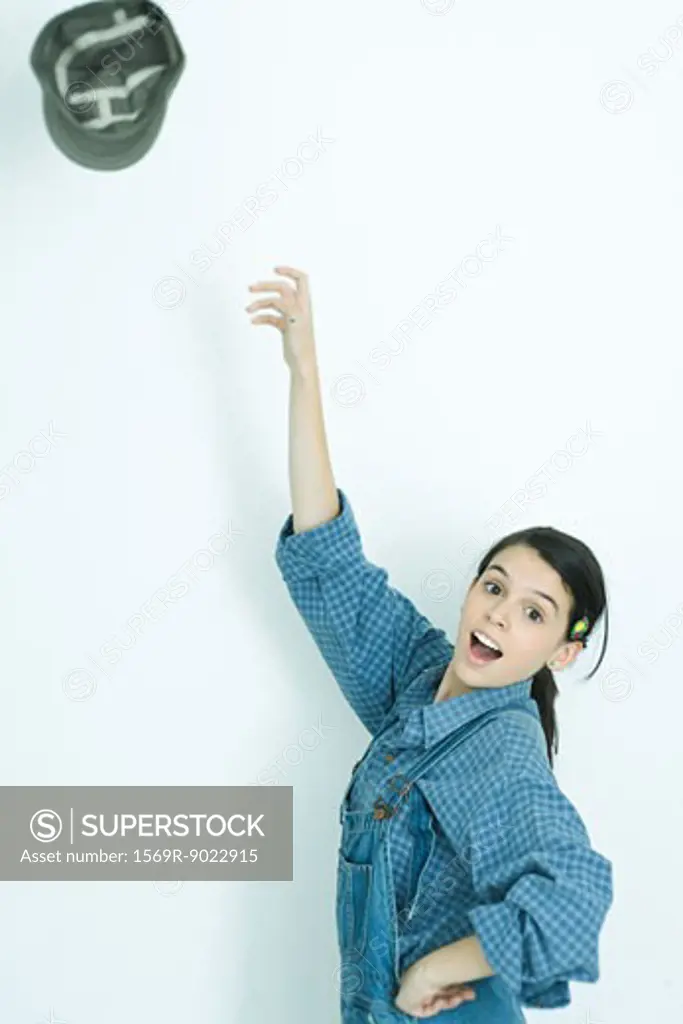 Teenage girl throwing hat into air, portrait