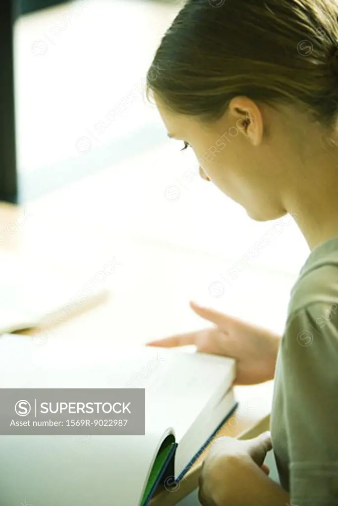 Female college student sitting at table in library, studying