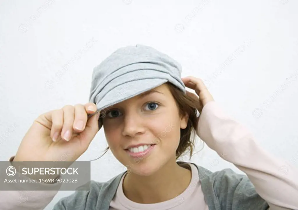 Young woman adjusting cap, portrait