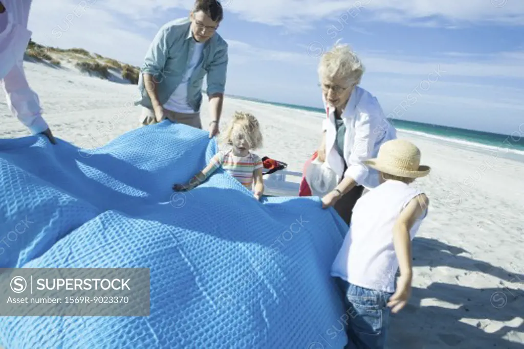 Family on beach, spreading blanket
