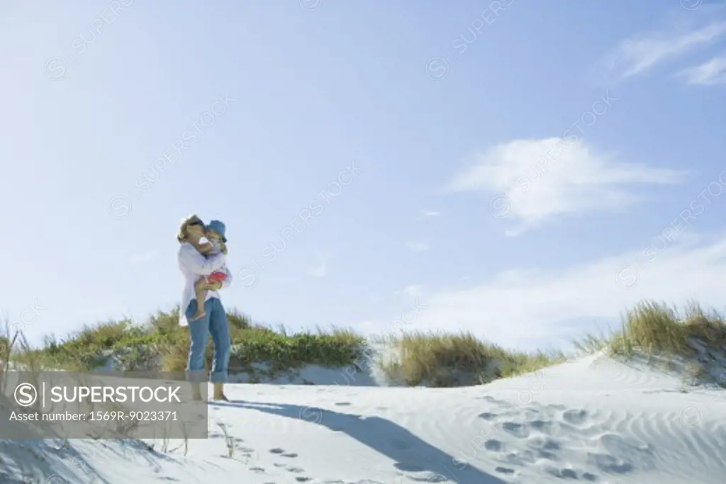 Mother and daughter standing on dune