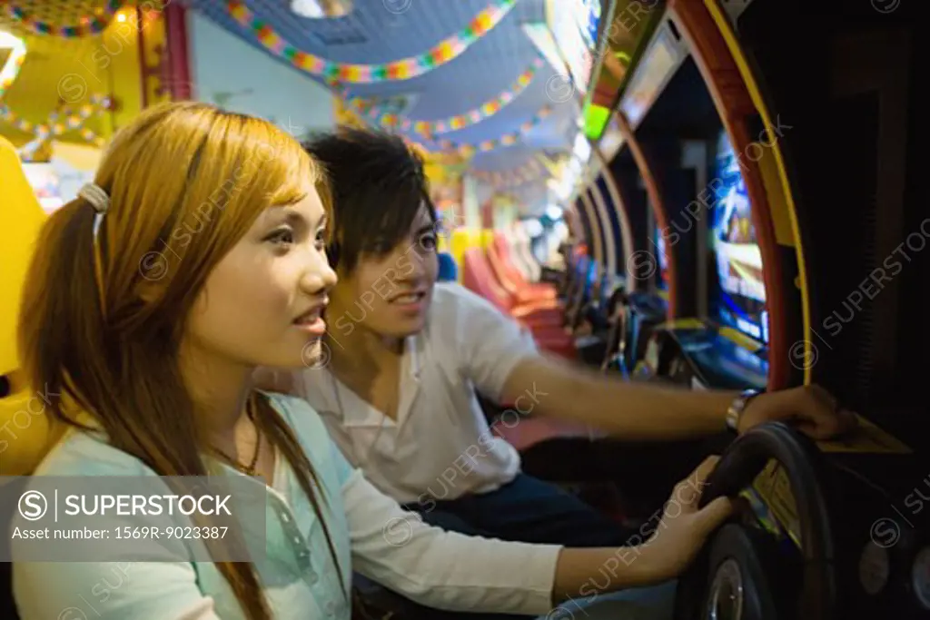 Teenage couple playing games in video arcade 