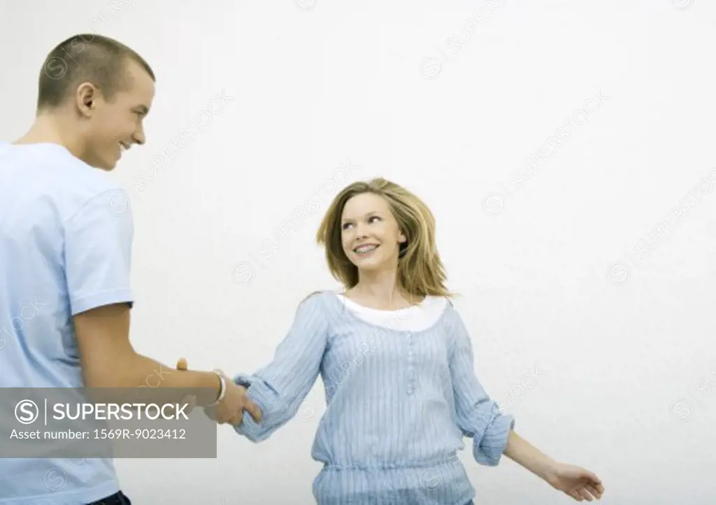 Young man taking young woman by the arm, both smiling