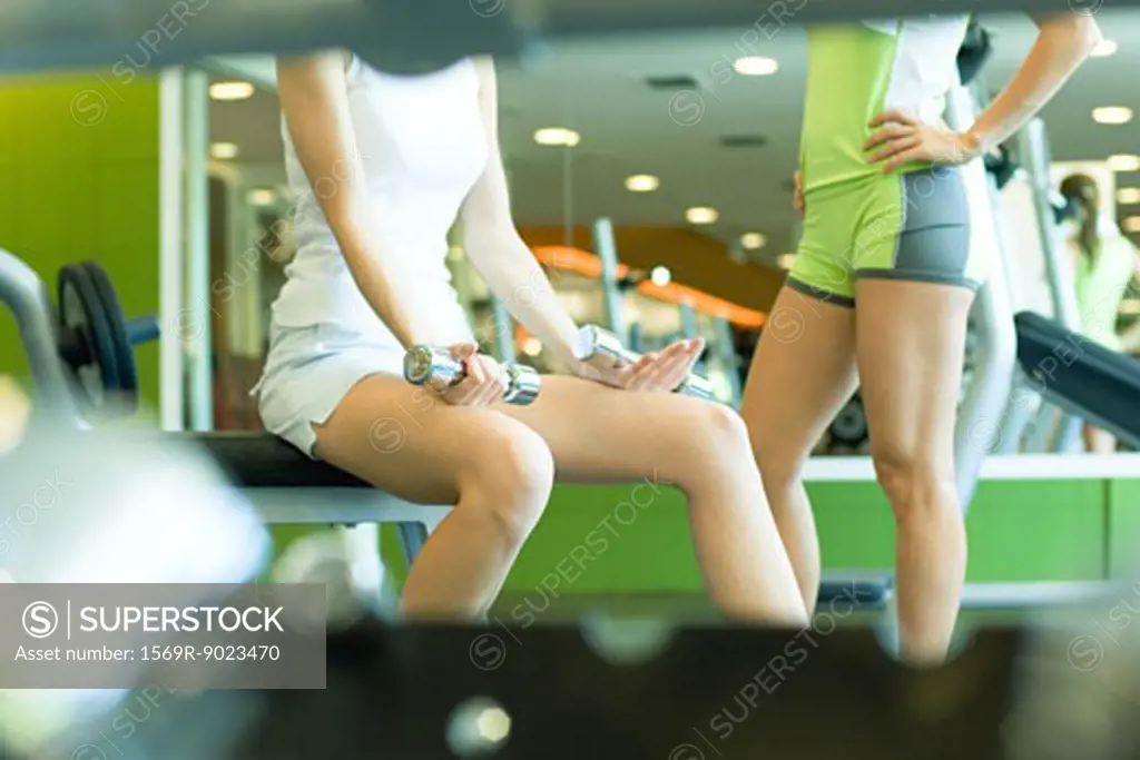 Two women standing in weight room, partial view