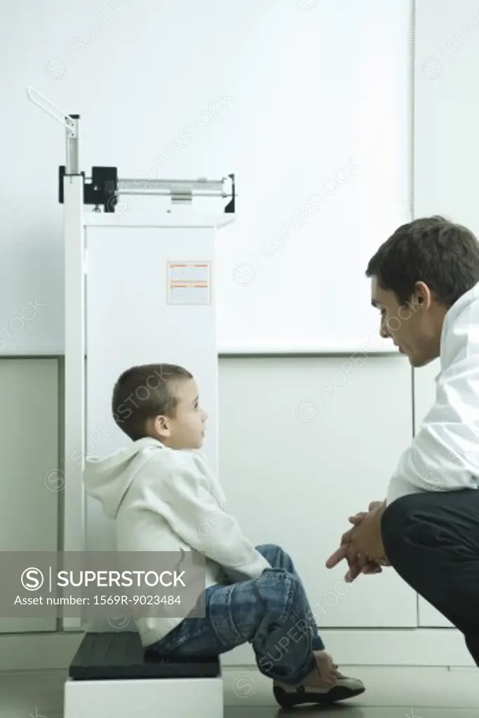 Boy sitting on scale talking to doctor in doctor's office