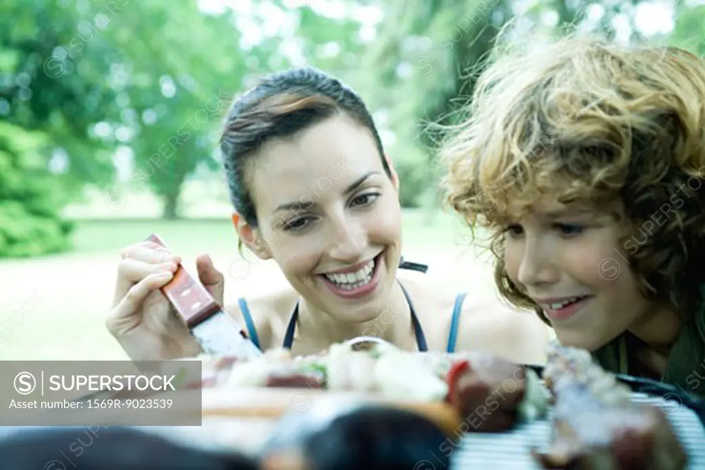 Family having cookout, woman and boy looking at food grilling