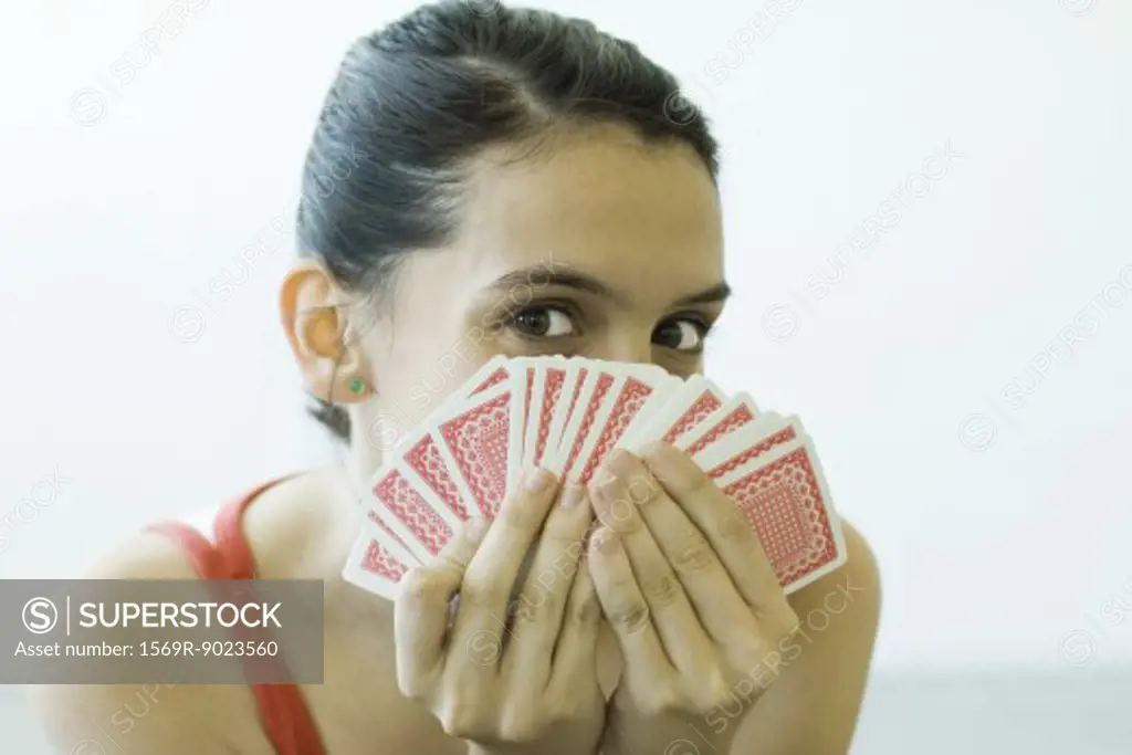 Teenage girl looking at camera over hand of cards