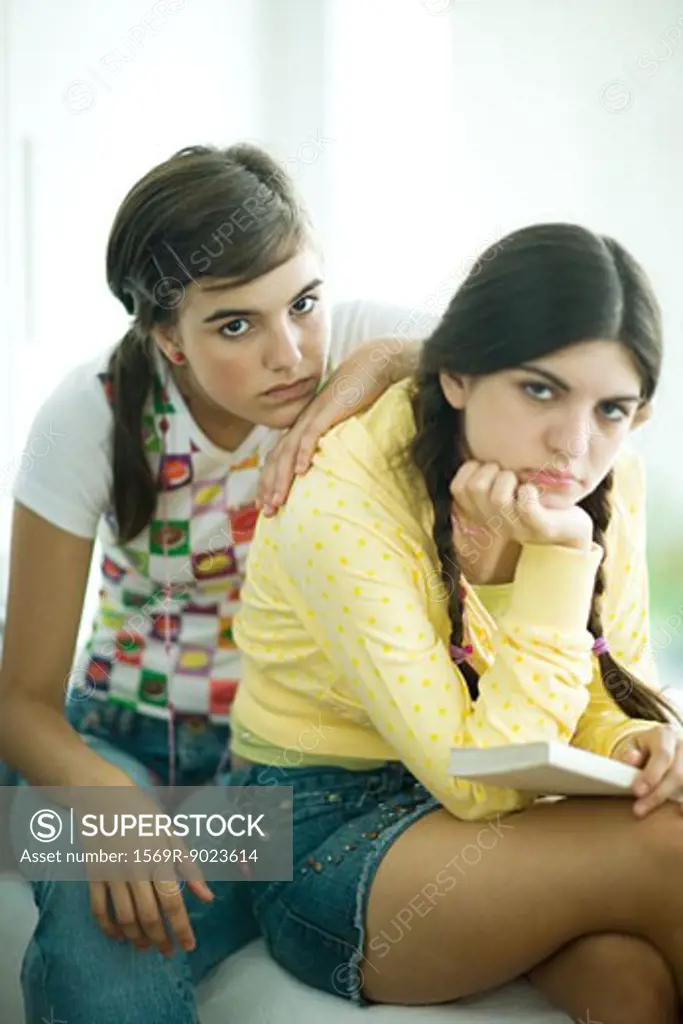 Two young female friends slouching and looking bored, looking at camera, portrait