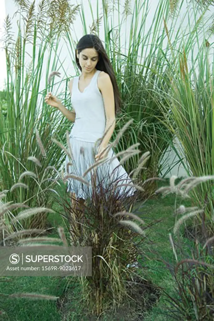 Woman standing among long grasses and reeds, full length
