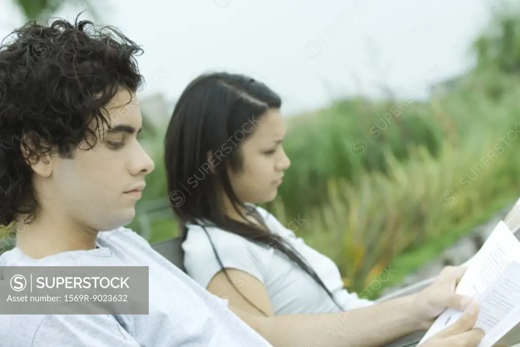 Young couple reading outdoors