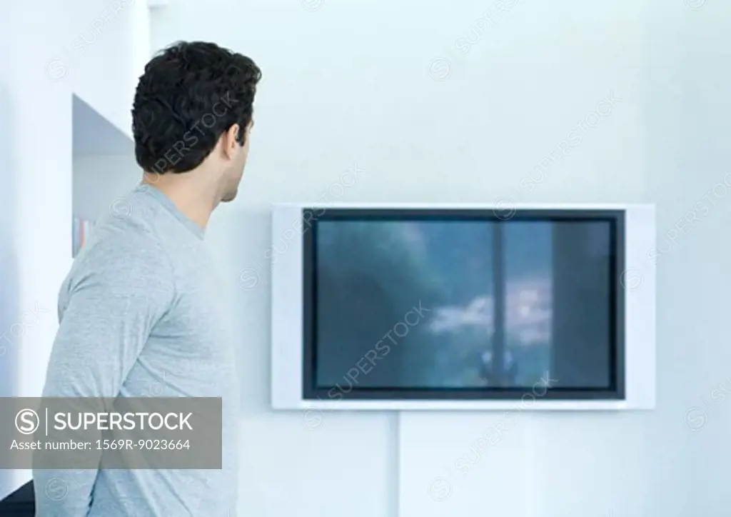 Man looking toward flat screen TV on wall