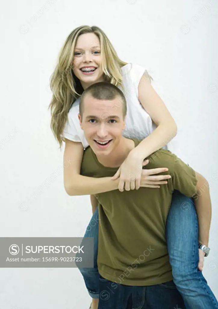 Young couple, teenage girl on young man's back, white background