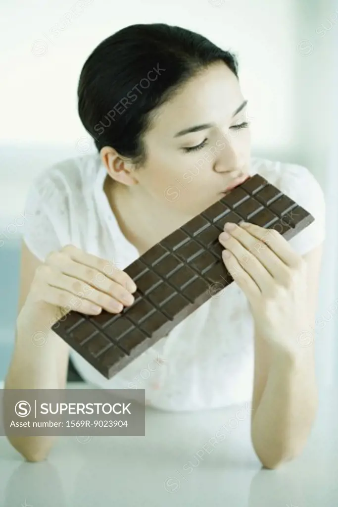 Woman kissing large bar of chocolate