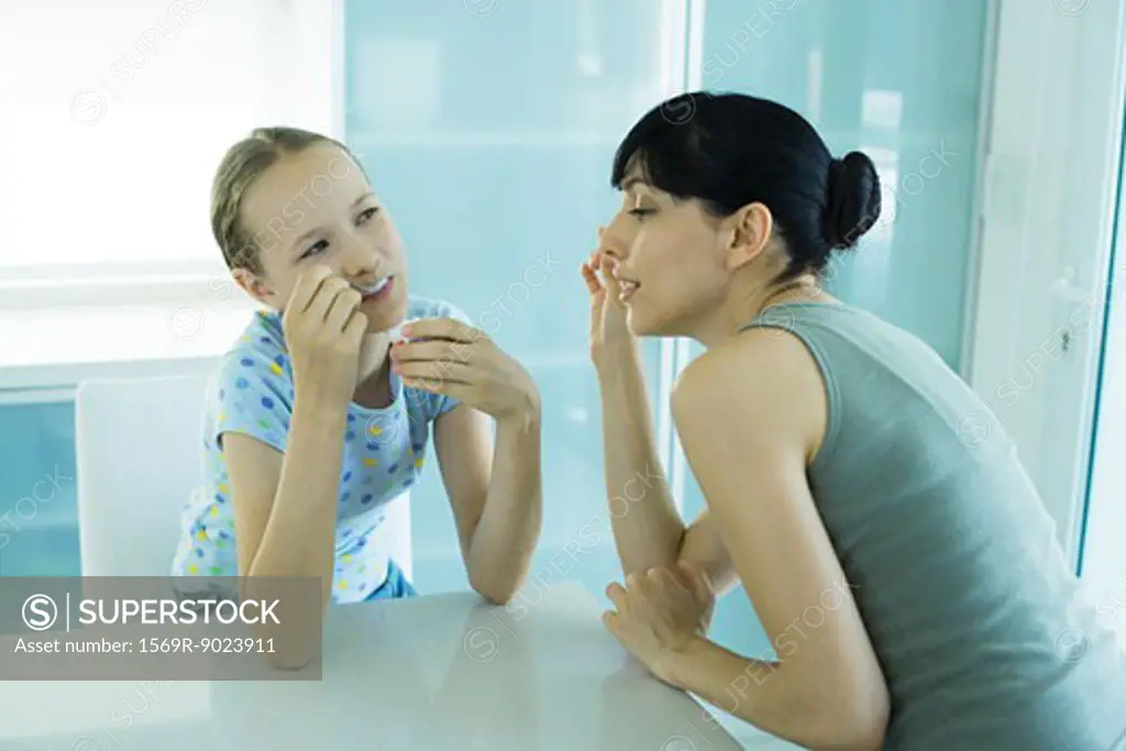 Girl eating ice cream dessert, woman leaning toward girl enviously