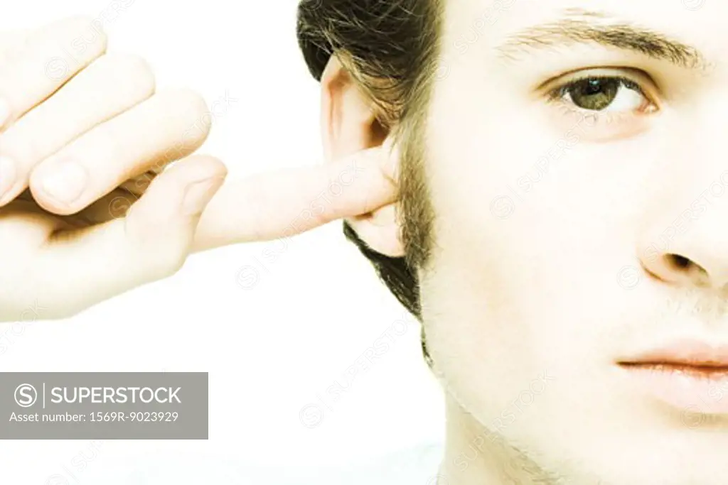 Young man plugging ear with finger