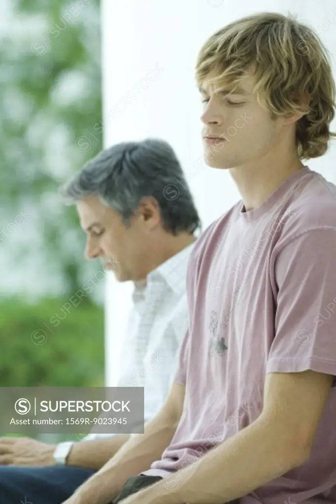 Young man sitting near father, eyes closed