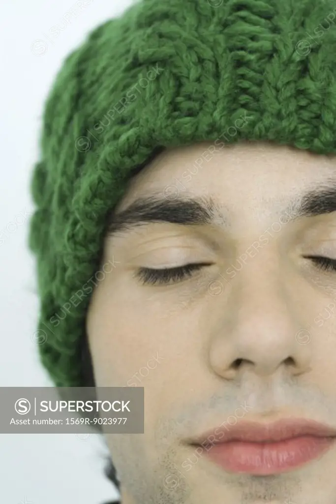 Young man wearing knit hat, eyes closed, portrait, close-up