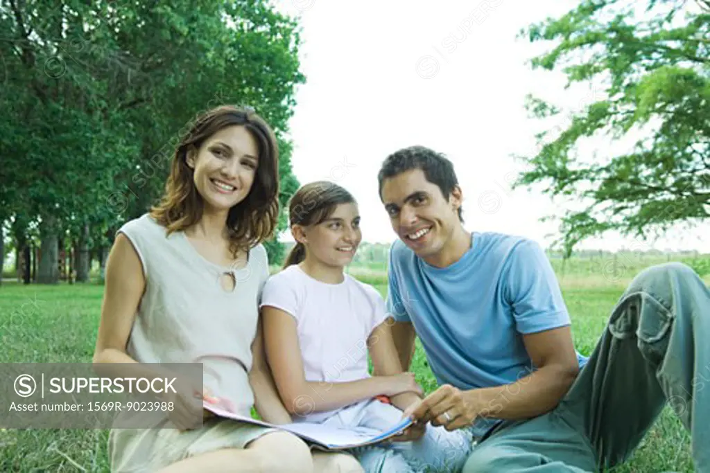 Family sitting outdoors, reading together