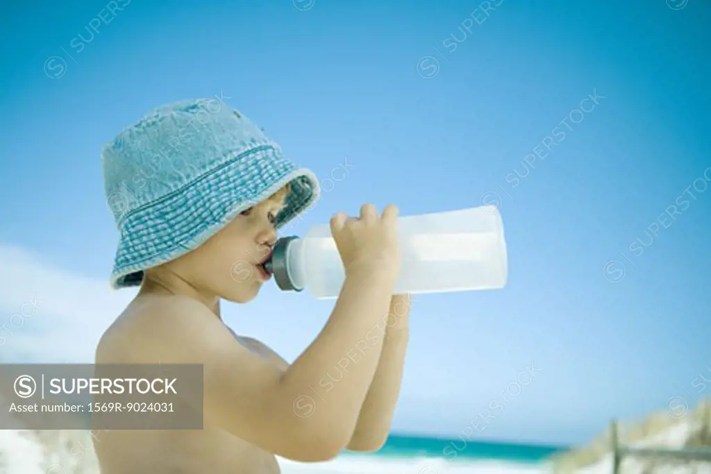 Child drinking water on beach