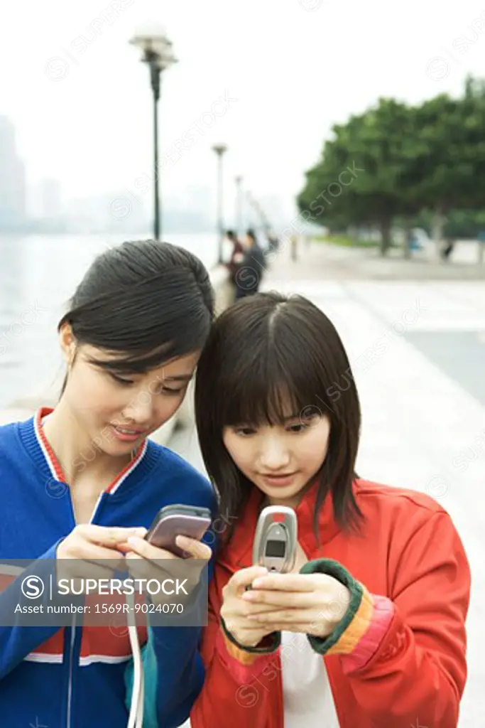 Two young women using cell phones