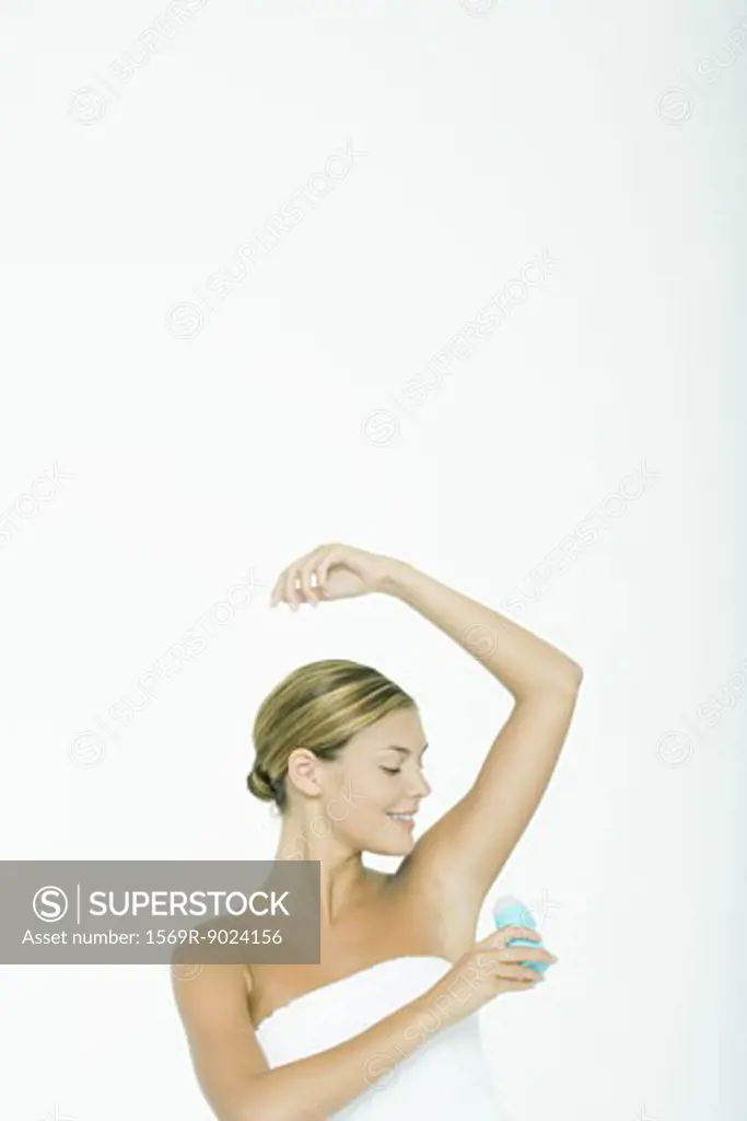 Young woman applying deodorant