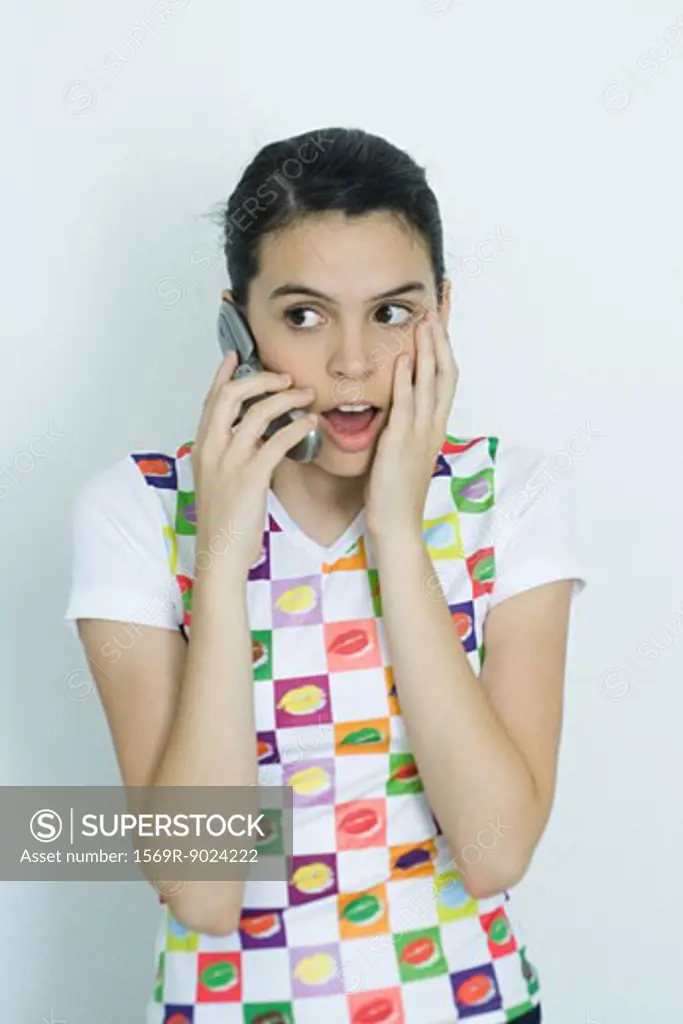 Teenage girl using cell phone, making surprised face, portrait
