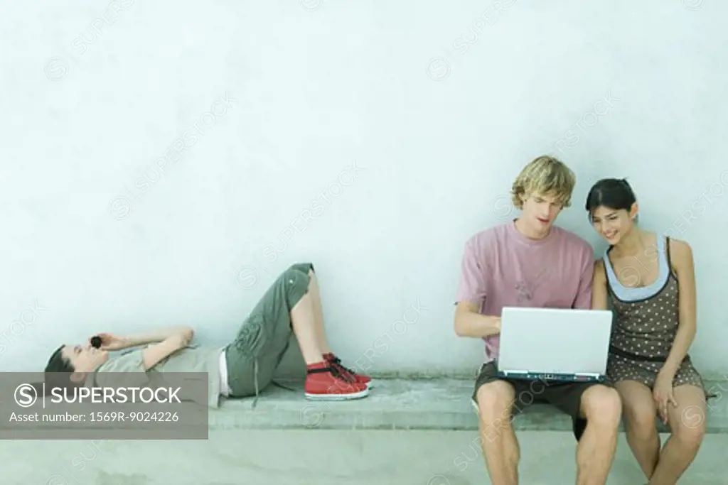 Group of young friends using laptop and cell phone