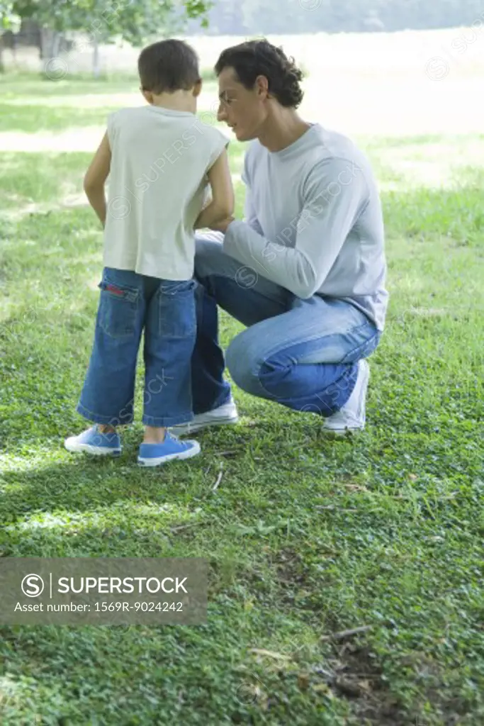 Man crouching next to boy, outdoors