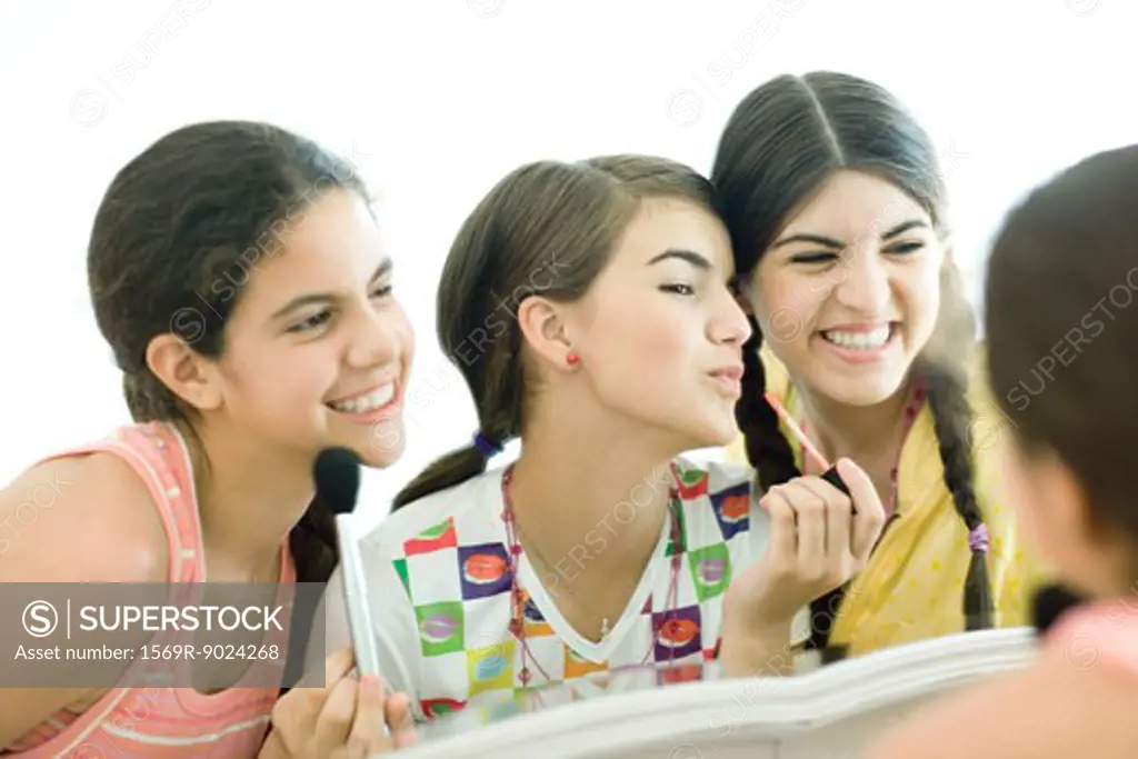 Three young female friends putting on make-up
