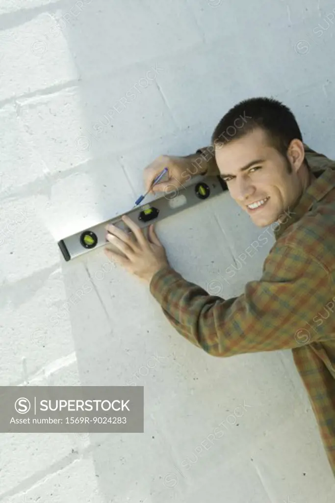 Man drawing line on wall with level