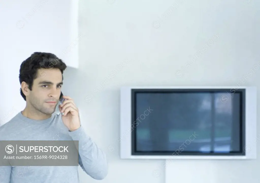 Man using phone, widescreen TV in background
