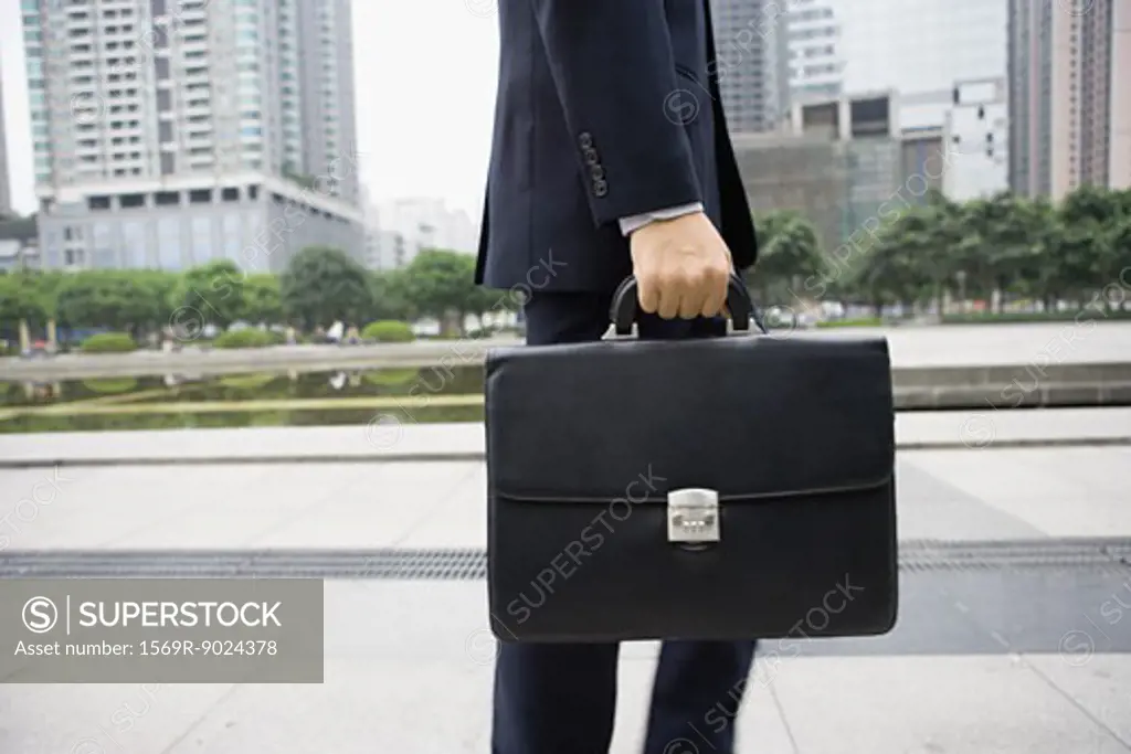 Businessman carrying briefcase, mid section