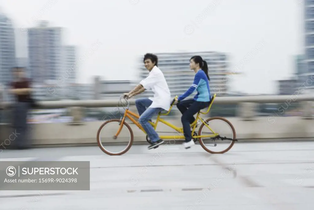 Couple riding tandem bicycle
