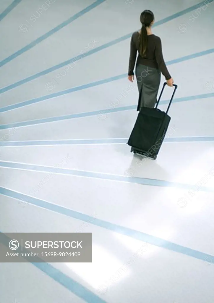 Woman walking with suitcase, high angle rear view