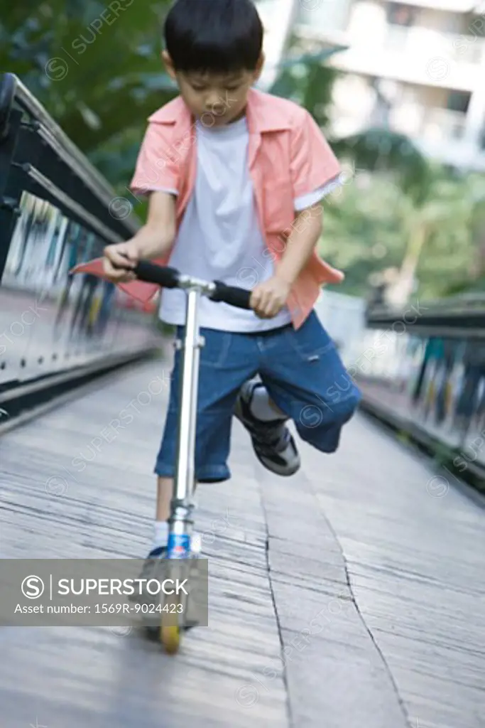 Boy playing on push scooter, full length