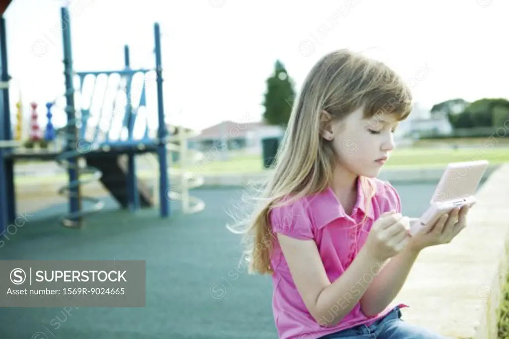 Child on playground, playing video game