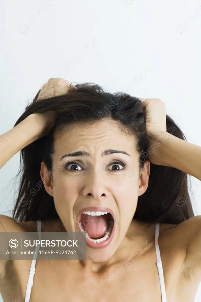 Woman pulling hair and screaming at camera, portrait