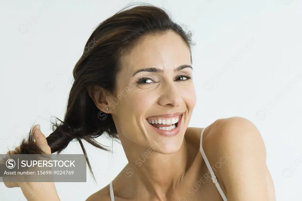 Woman twisting hair to the side, smiling at camera, portrait