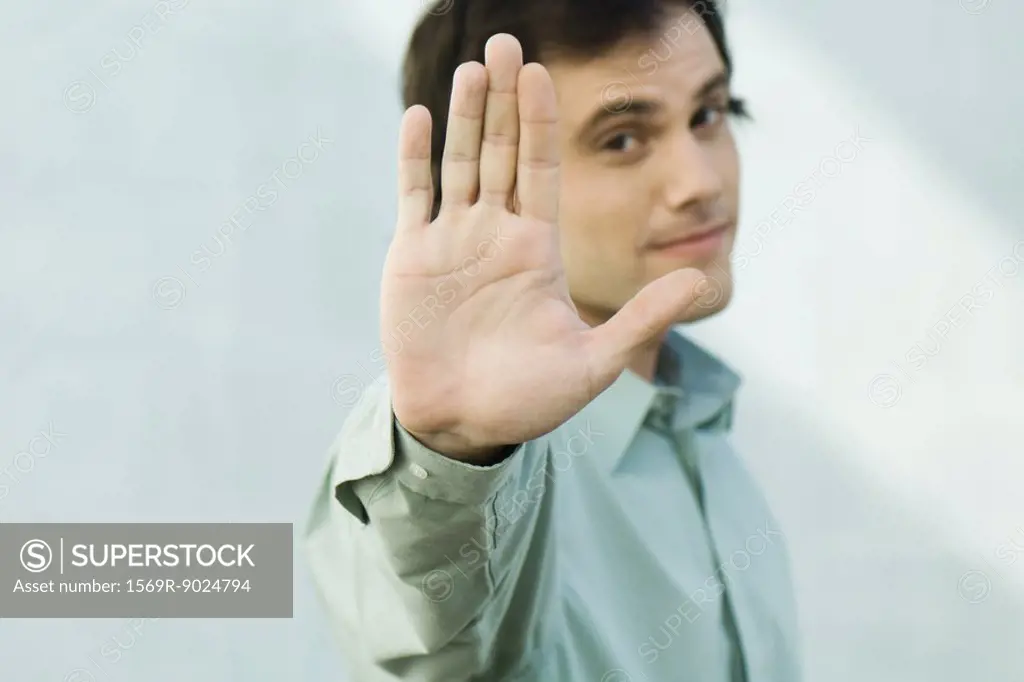 Man holding up palm to camera, portrait