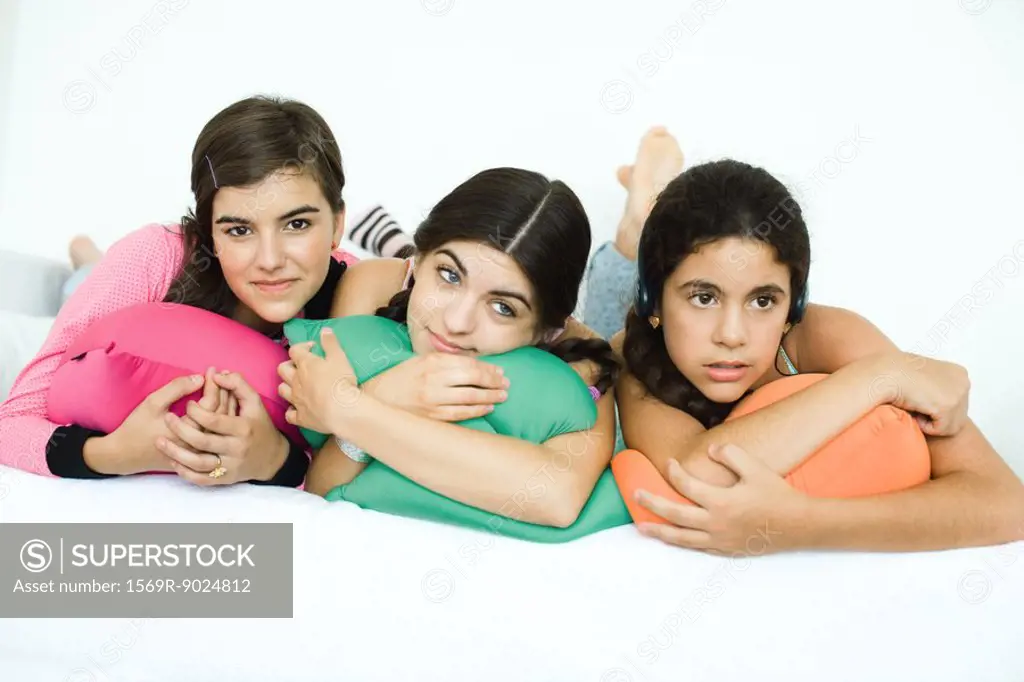 Three young female friends lying with heads on cushions