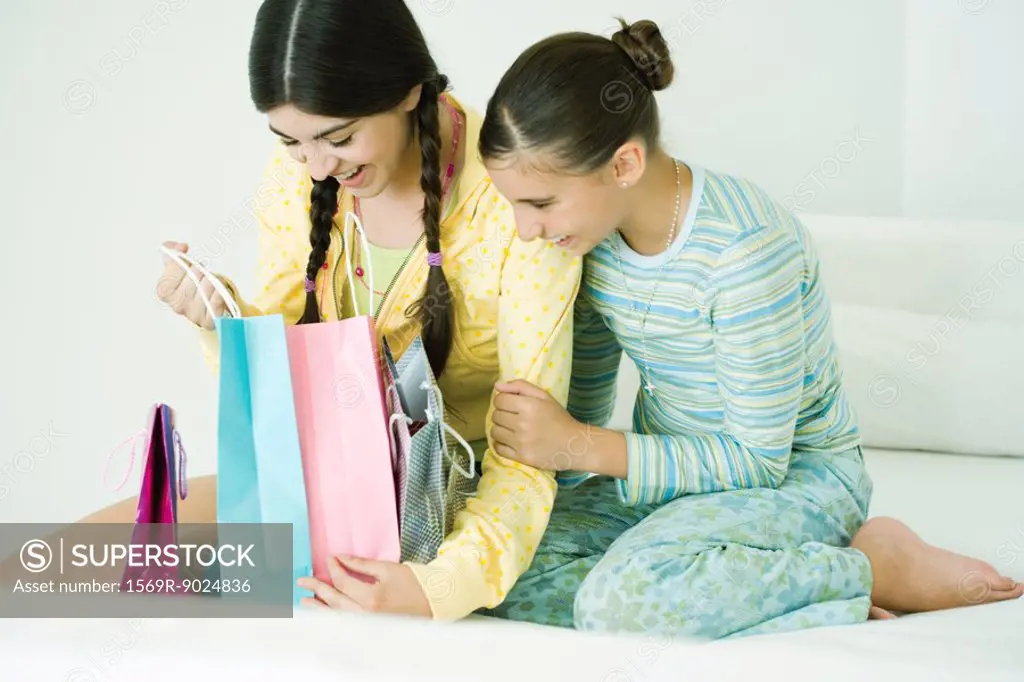 Two young female friends, one opening up gift bags