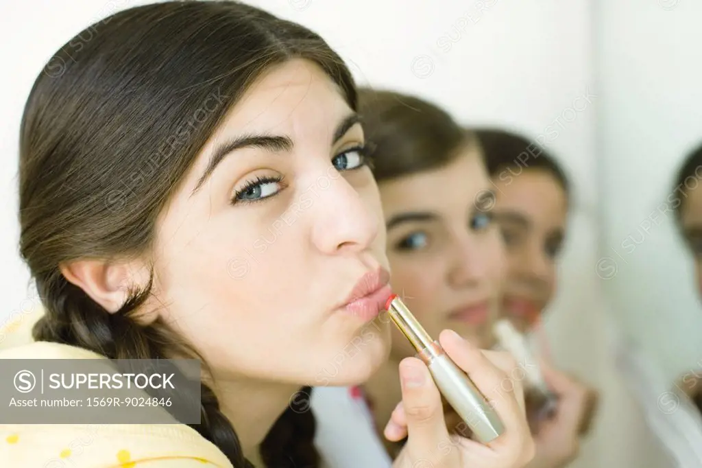Young female friends putting on make-up