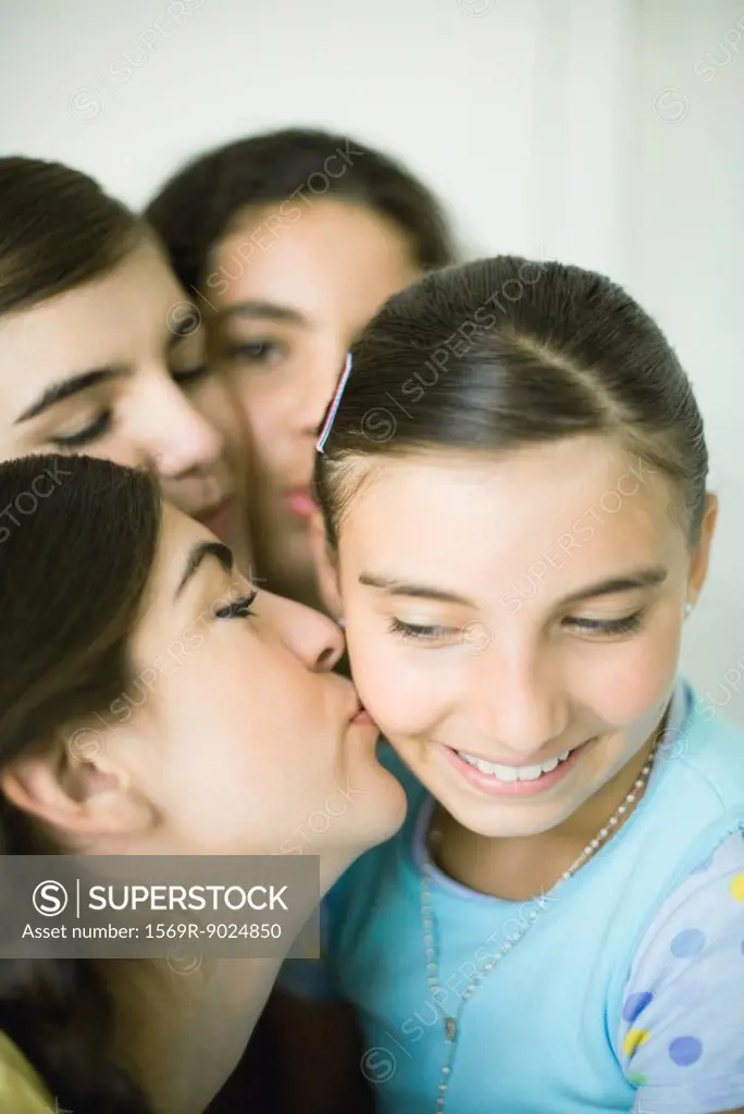 Young female friends kissing younger girl´s cheek