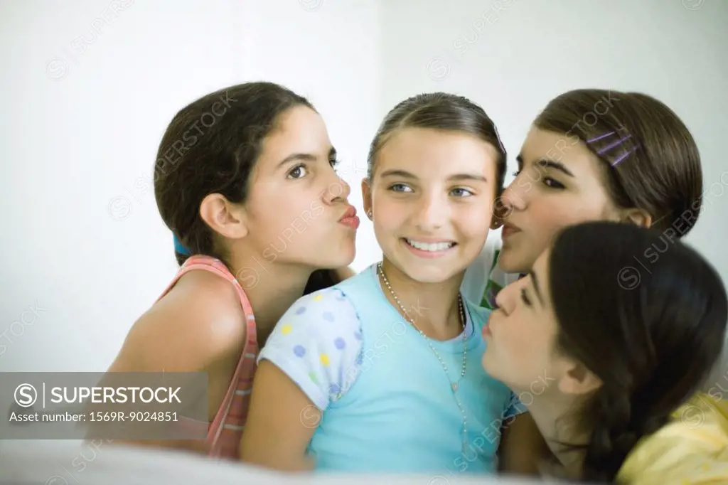 Young female friends kissing younger girl´s cheeks