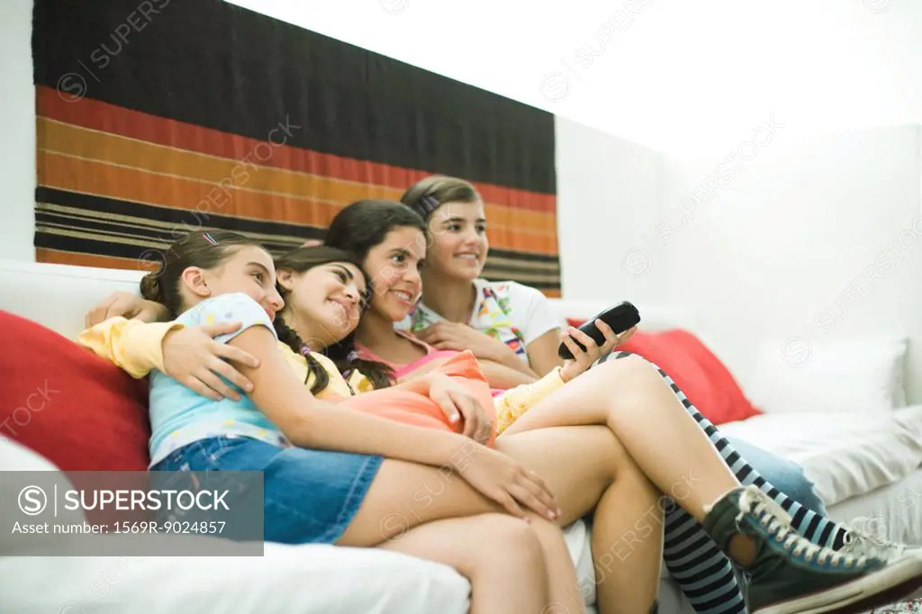 Young female friends sitting on sofa, watching TV together