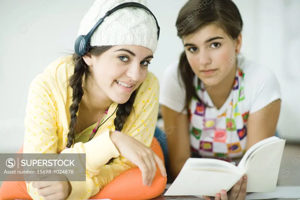 Two young female friends lying on floor, doing homework together