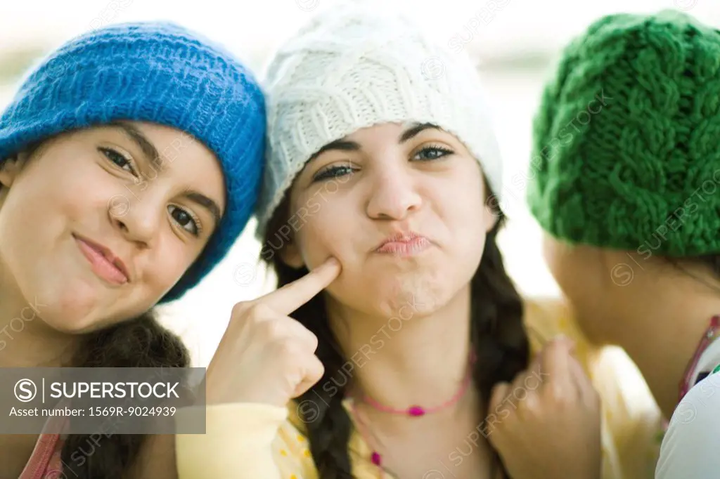 Young female friends wearing knit hats, making faces