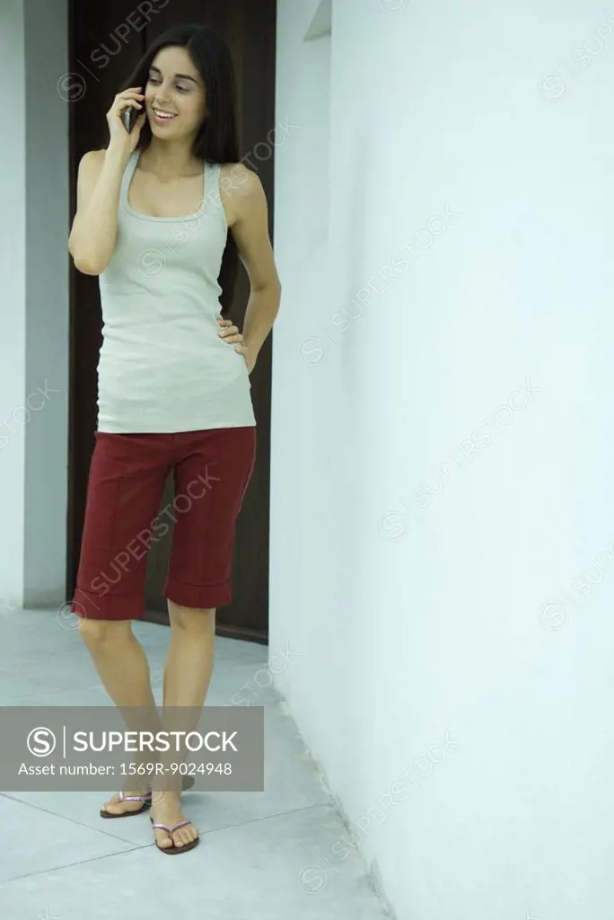 Woman standing using phone, full length portrait