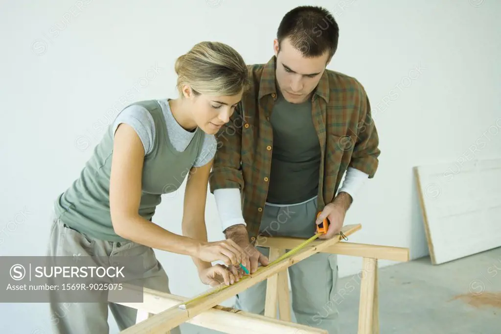 Couple making measurements on wood plank